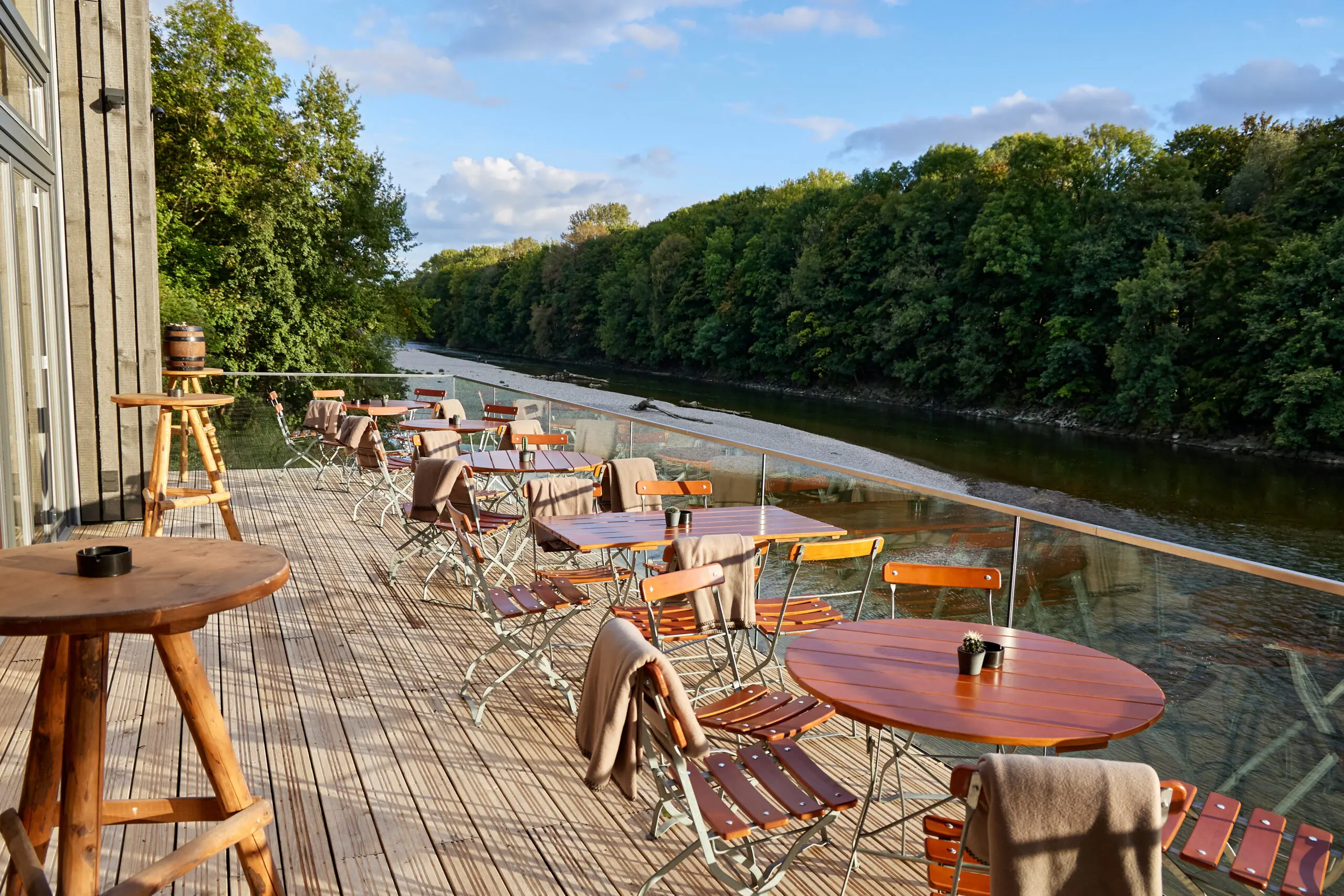 Tische und Stühle auf der Terrasse der Floßlände mit Blick auf den Lech