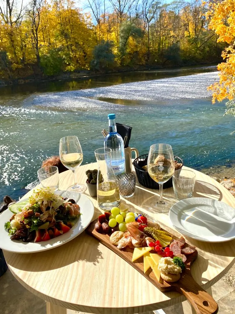 Gedeckter Tisch mit Speisen und Weingläsern direkt am Lech an der Floßlände