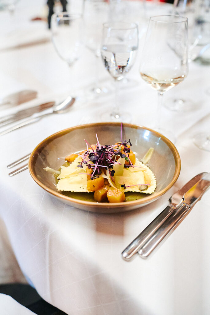 Kürbis-Schlutzkrapfen mit Sprossen in einer goldfarbenen Schale an der Floßlände in Augsburg