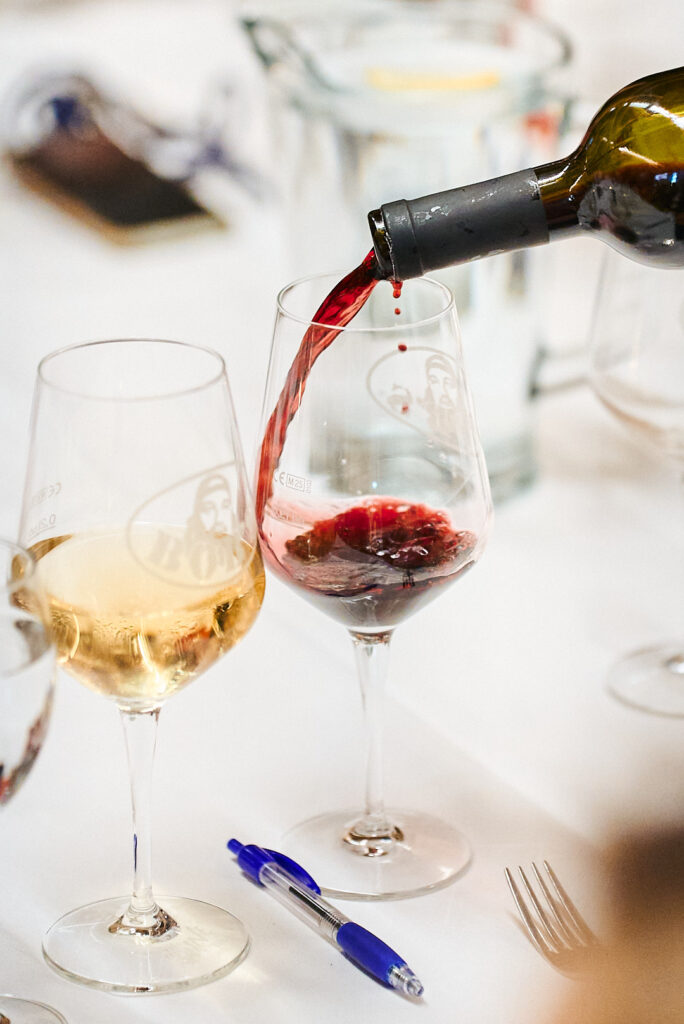 Rotwein wird neben einem gefüllten Weißweinglas eingeschenkt an der Floßlände in Augsburg