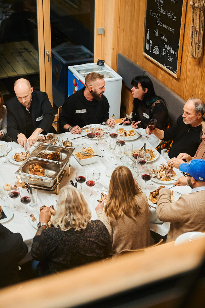 Gäste teilen die Südtiroler Speisen an einer langen Tafel an der Floßlände in Augsburg